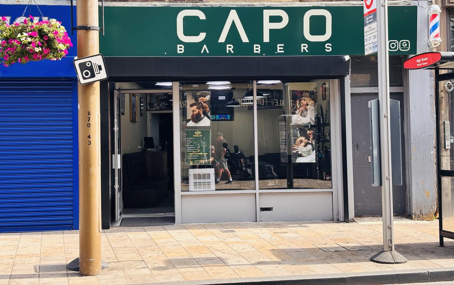 Inside Capo barbers: black chairs, mirrors, and the green CAPO sign on the wall